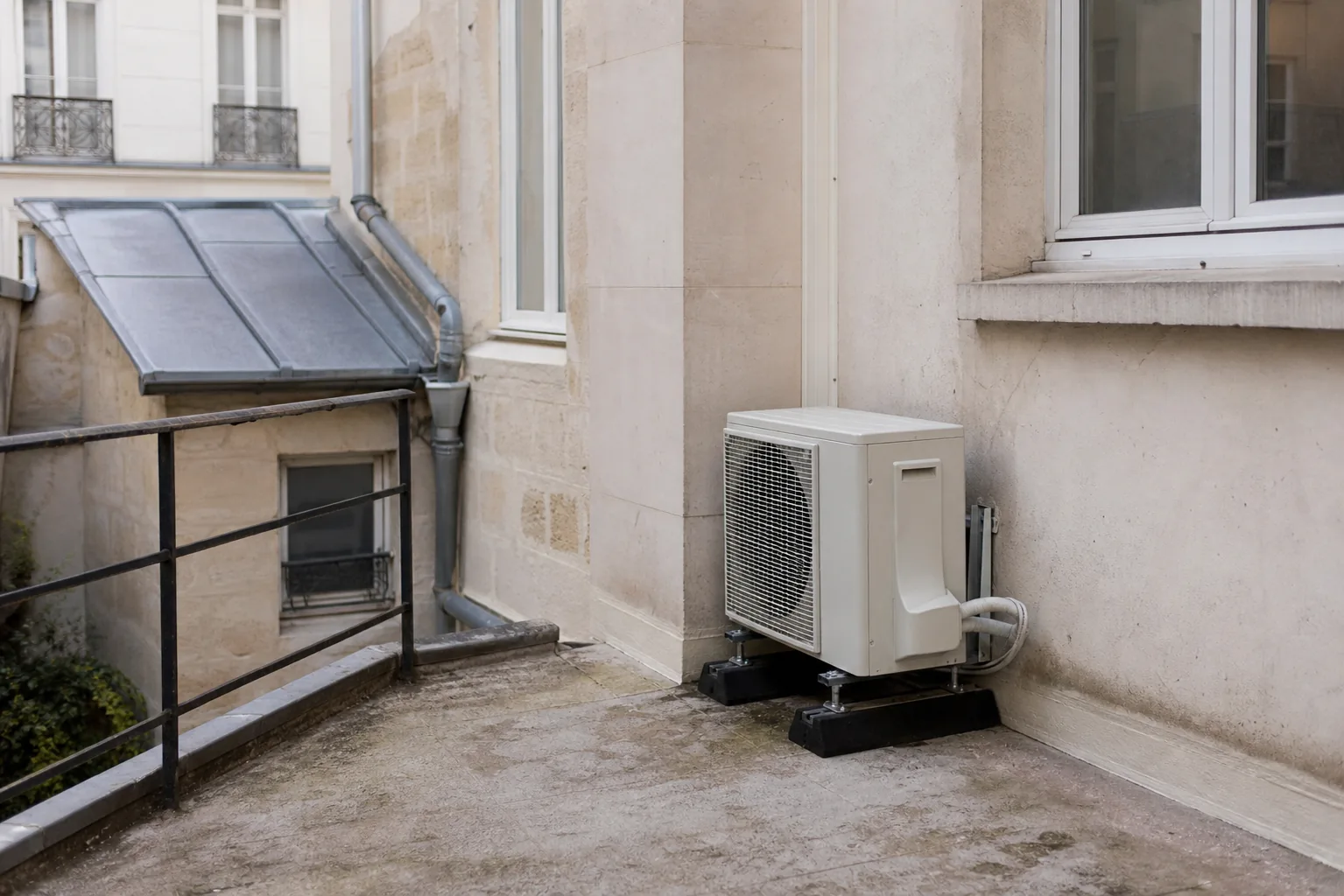 Unité extérieure de climatisation posée discrètement sur une façade de cour parisienne